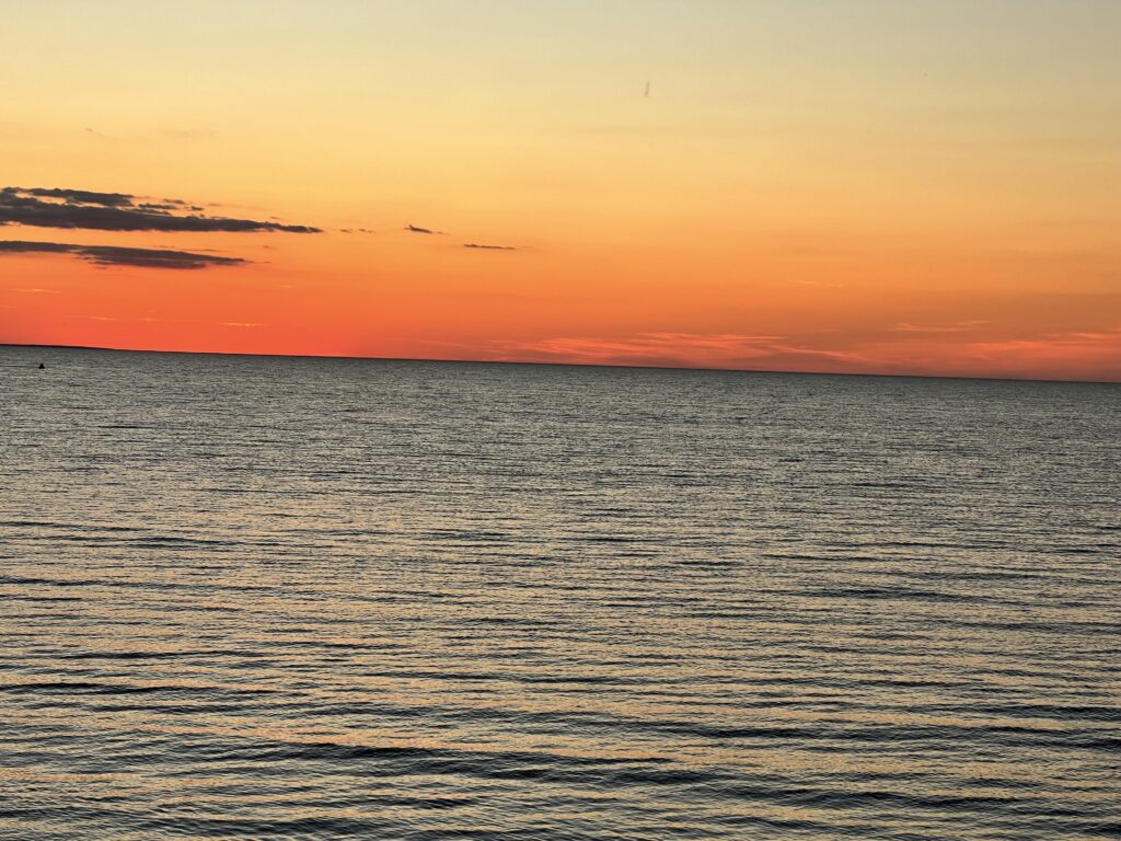 Vibrant orange and gold sunset over calm waters of the Saginaw Bay in Michigan